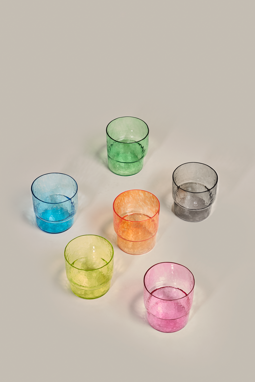Top-down view of 6 stackable colored Pool tumblers by Cornelius Réer showing water-ripple texture