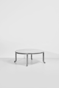 Low mirror-polished stainless steel coffee table with curved tubular legs by Hannah Kuhlmann